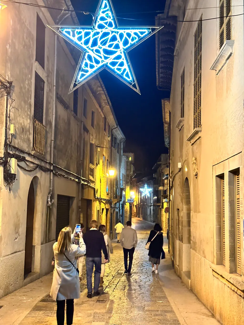 Star-shaped Christmas lights over a narrow street in Pollença old town