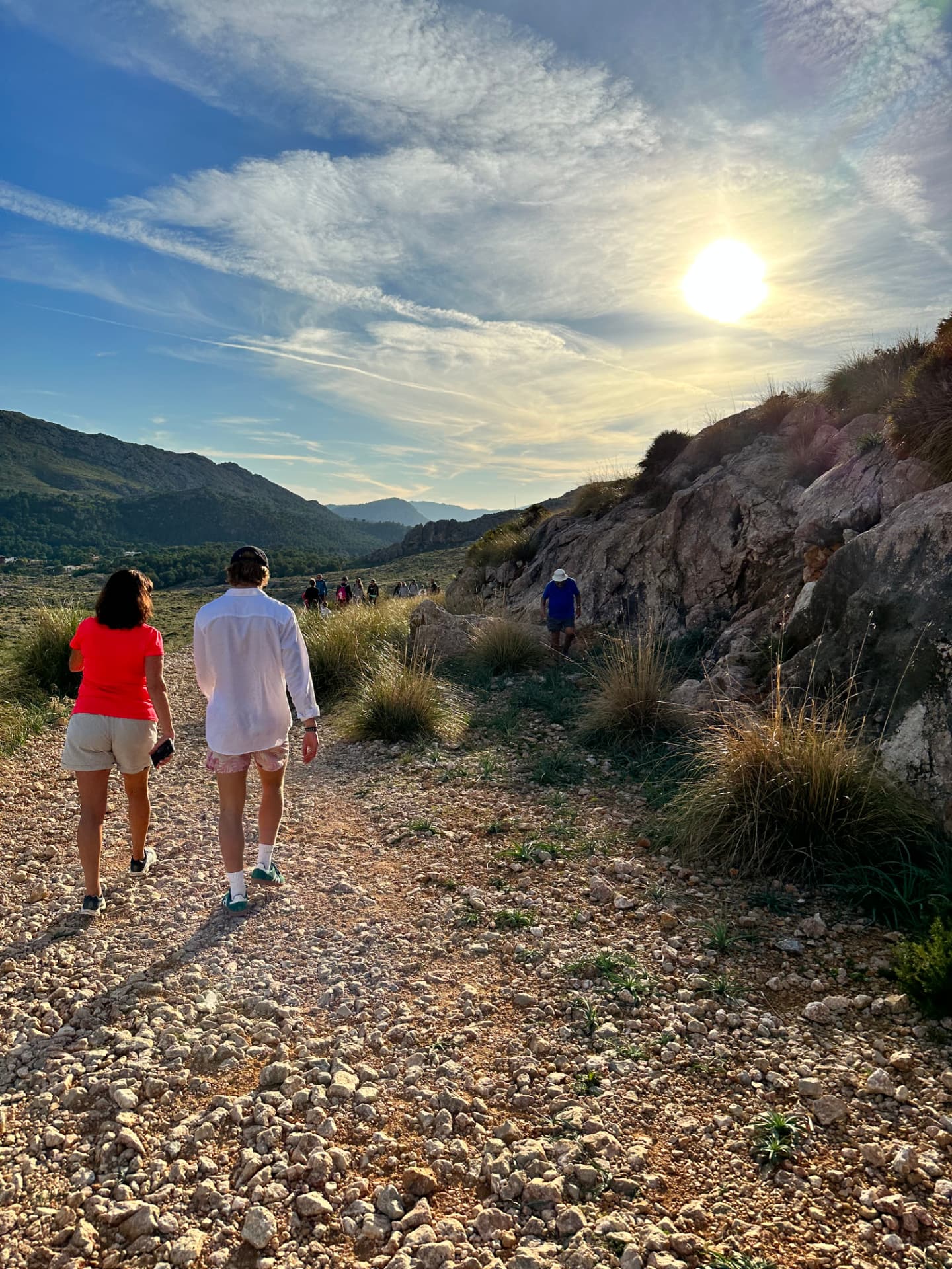 Two walkers on a sunny rocky trail in the hills near Pollença