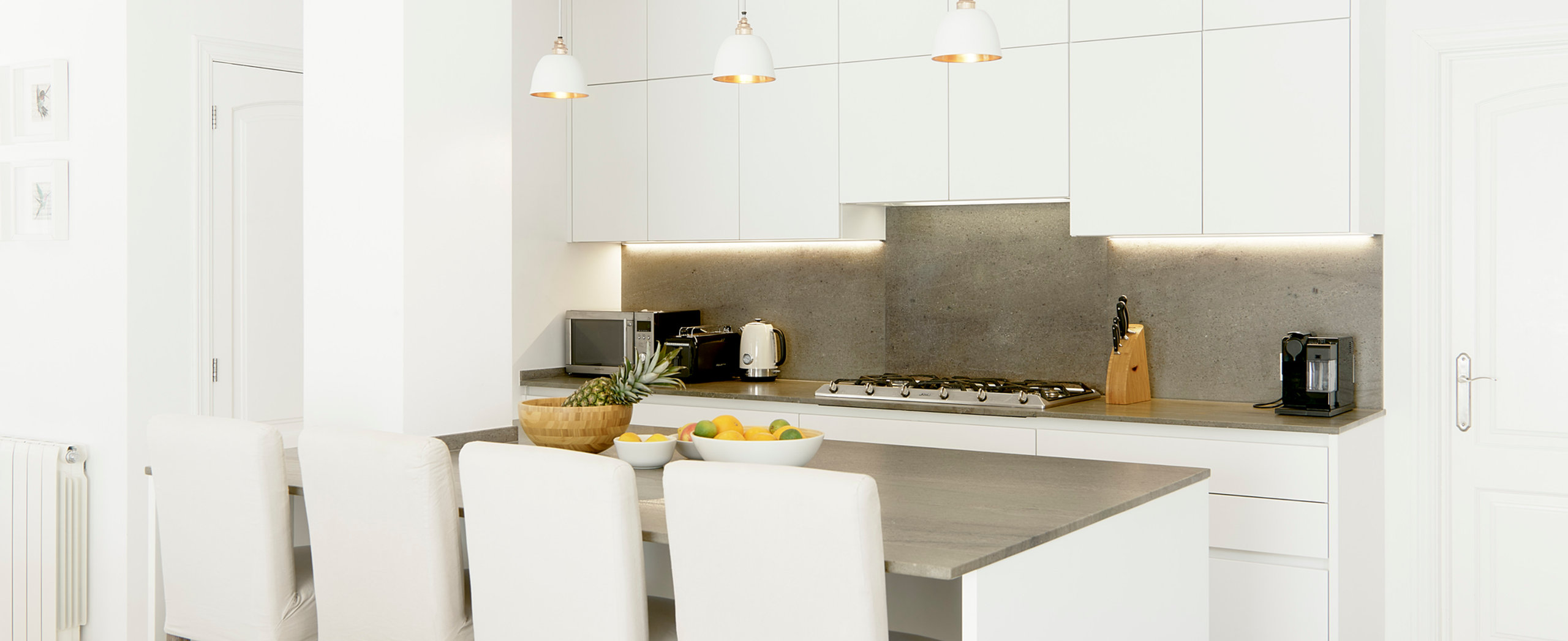 Villa Esquina's modern white kitchen and island dining area