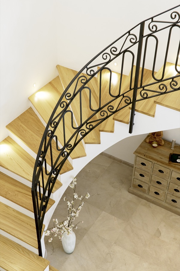 The curved staircase and wooden chest of drawers