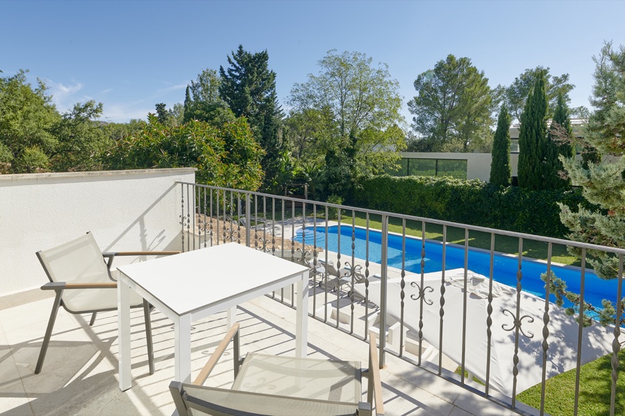 A bedroom balcony overlooking the swimming pool and garden