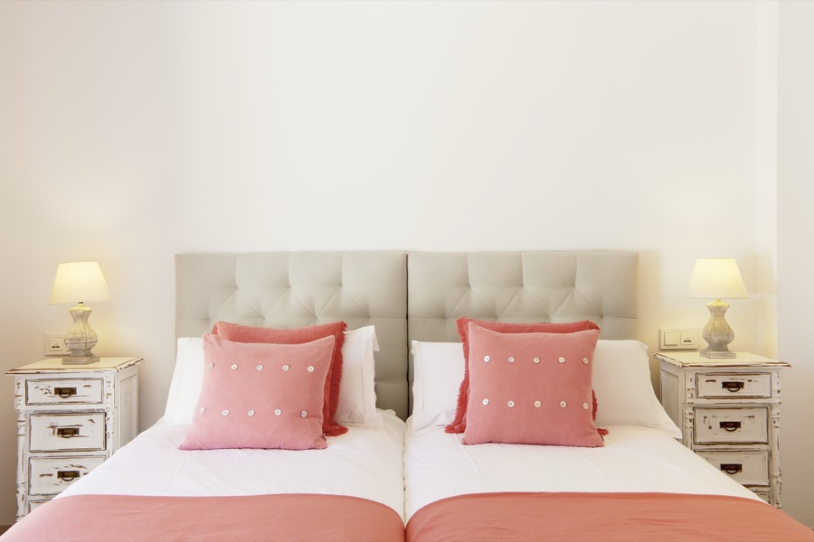 A twin bedroom with coral cushions and matching bedside tables