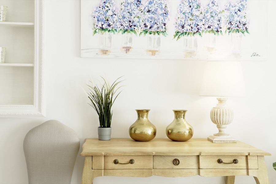 A bedroom console table with lamps, plants and floral artwork