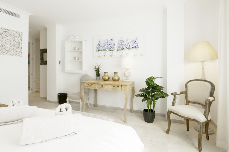 A bright double bedroom with occasional chairs and console table