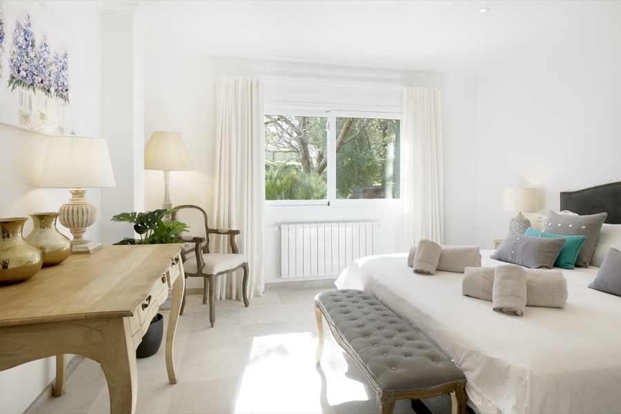 A bedroom with writing desk and garden view