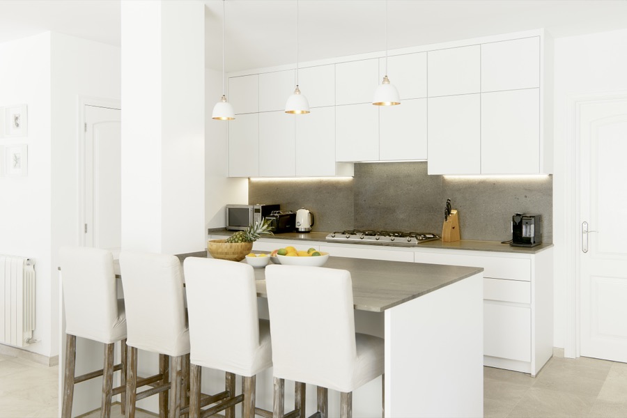 The white kitchen with central island and bar stools